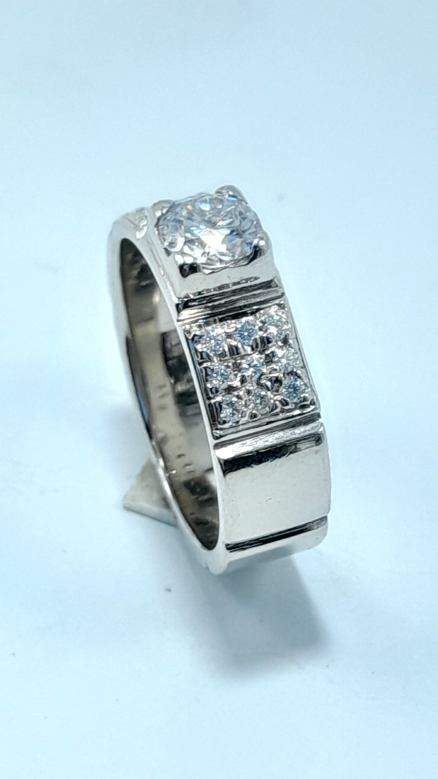 Silver ring with diamond accents on a light blue background